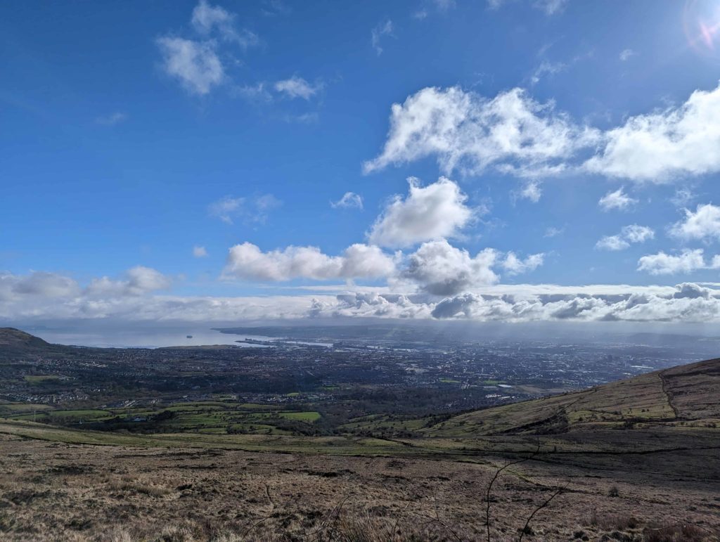 Breathtaking views over Belfast from The Summit Trail Divis Mountain in Northern Ireland. Blue skies and rolling green hills.