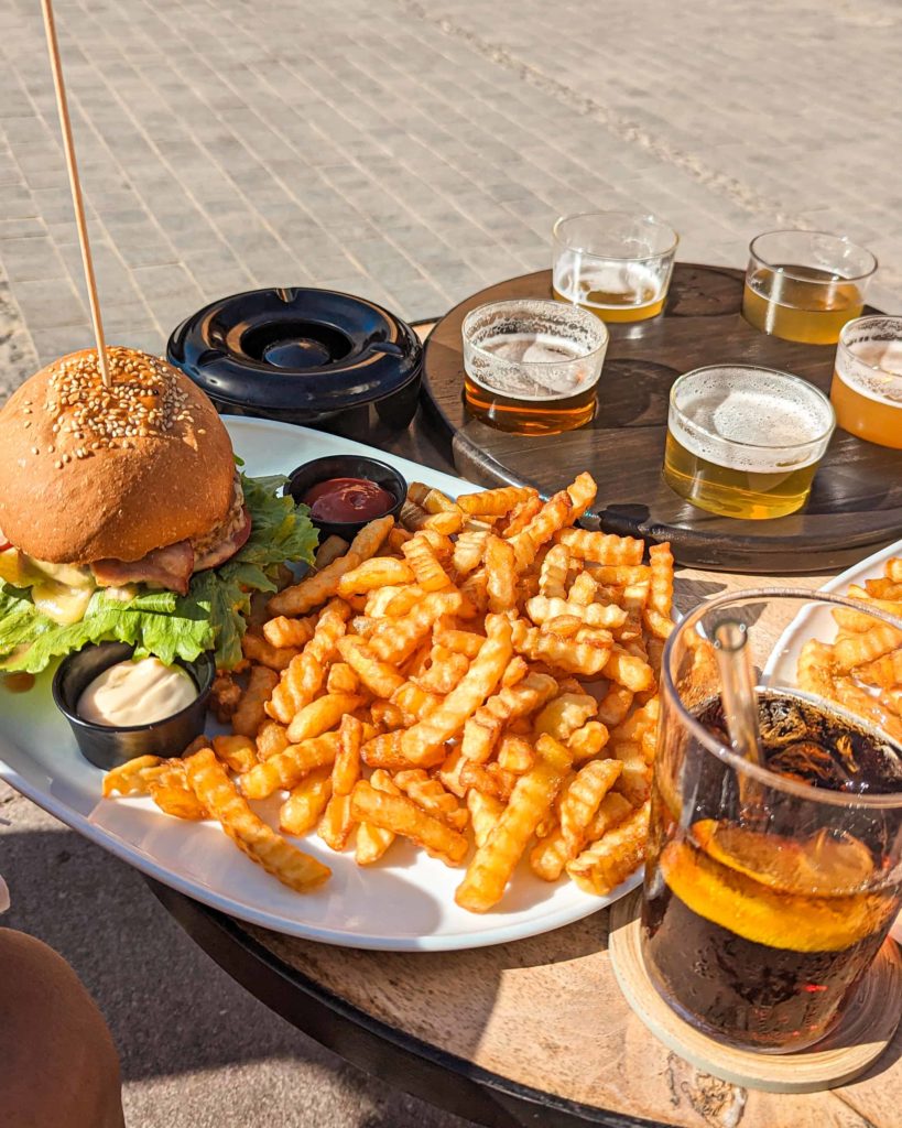 Our burger and chips at Waterfall Bar, Corralejo, Fuerteventura. Also showing a flight of beers and  glass of coke on the table.