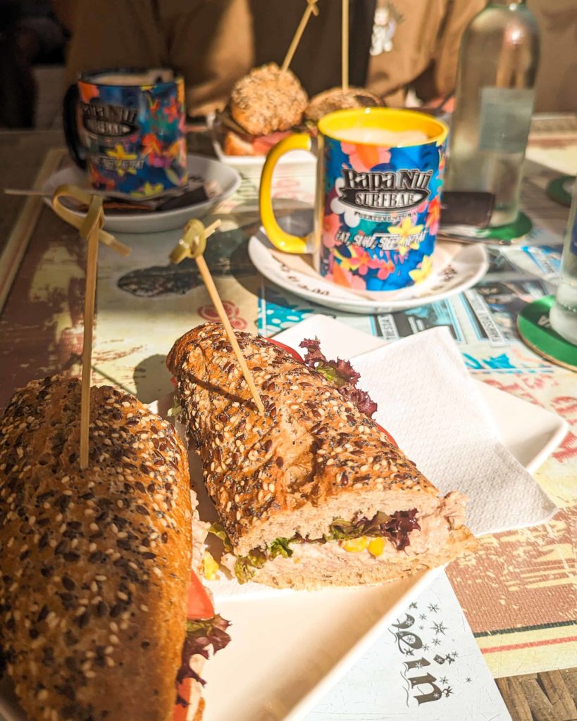 a picture showing the tuna baguette i ordered at Rapa Nui, and a colourful mug with flowers on it with my coffee in it.