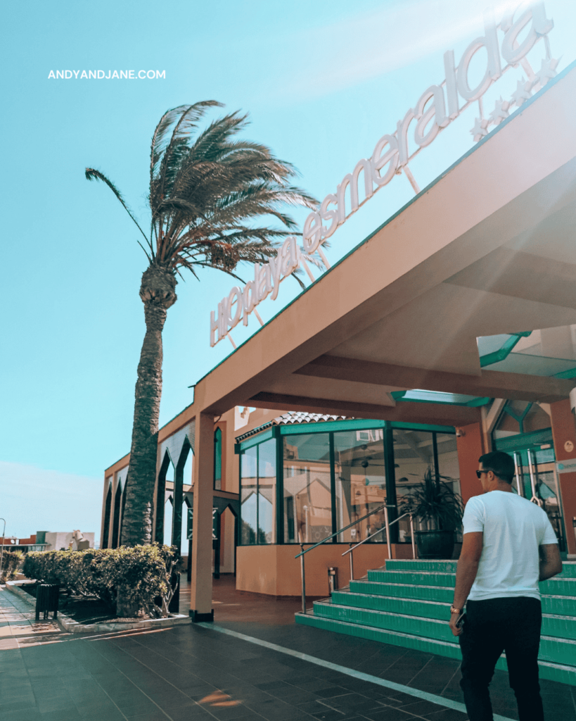 the front of the hotel with a palm tree swaying in the wind