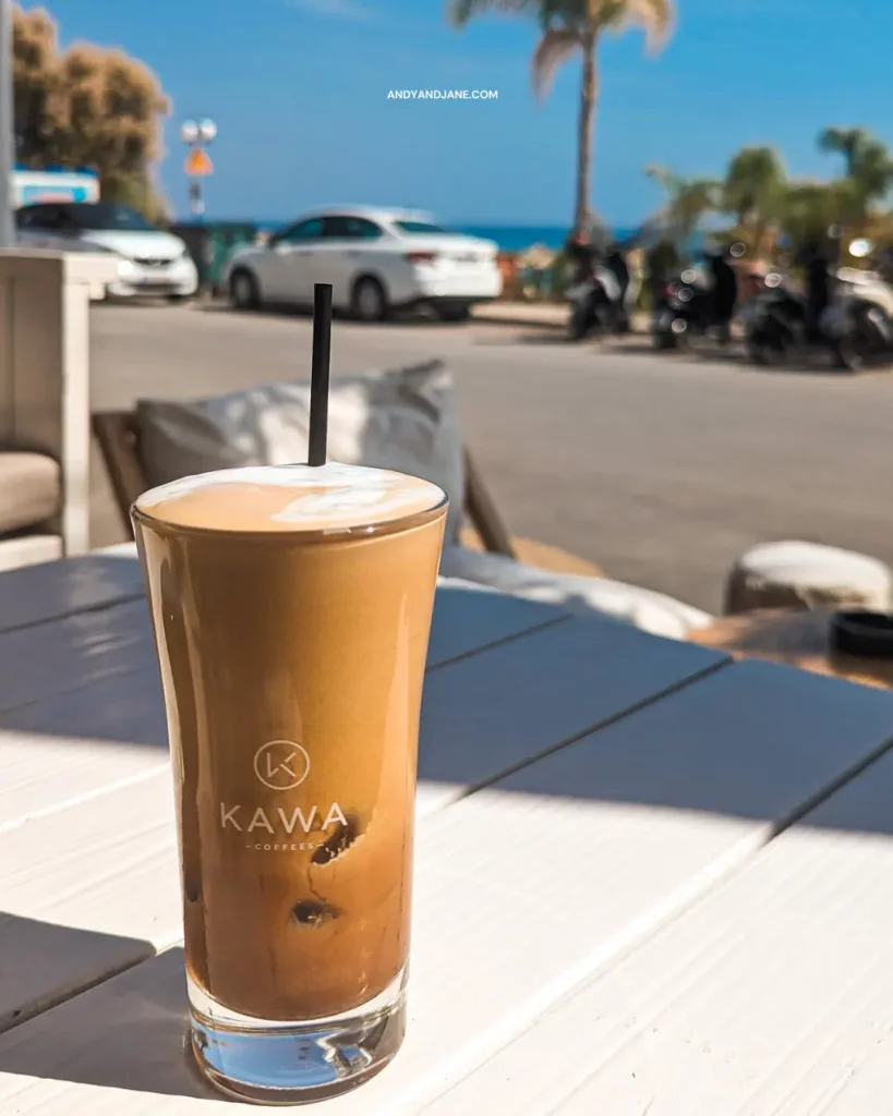 A cup of coffee on a table in Jack's Beach Bar, by the ocean, offering a serene view of the waves and a perfect spot to relax and enjoy the scenery.