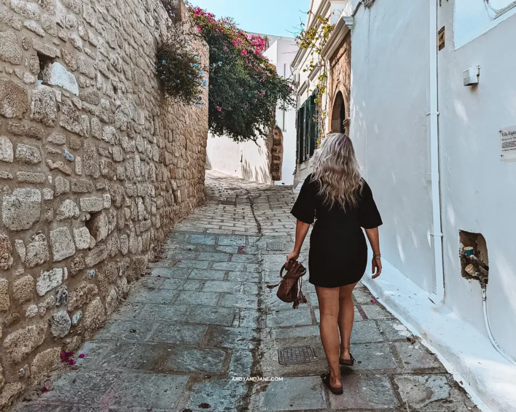 Jane wandering through the cobbled streets of Lindos wearing a black dress and sandals.