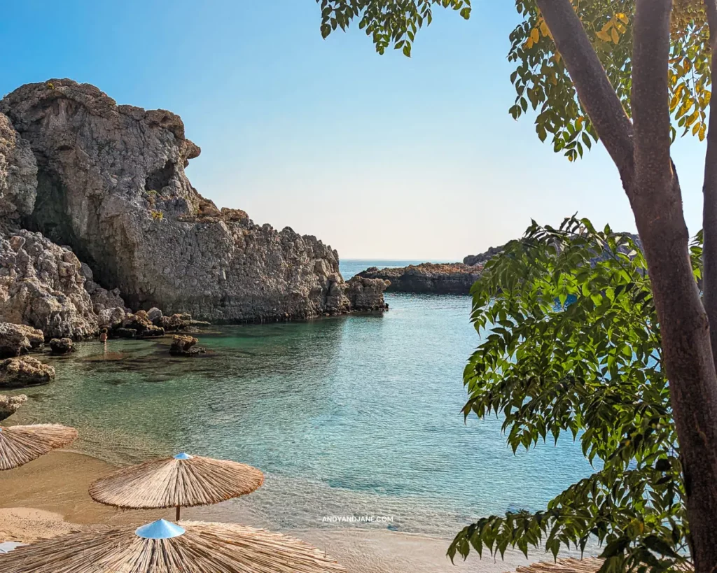 A scenic beach at St.Paul's Bay, with colourful umbrellas and a majestic rock formation in the background.