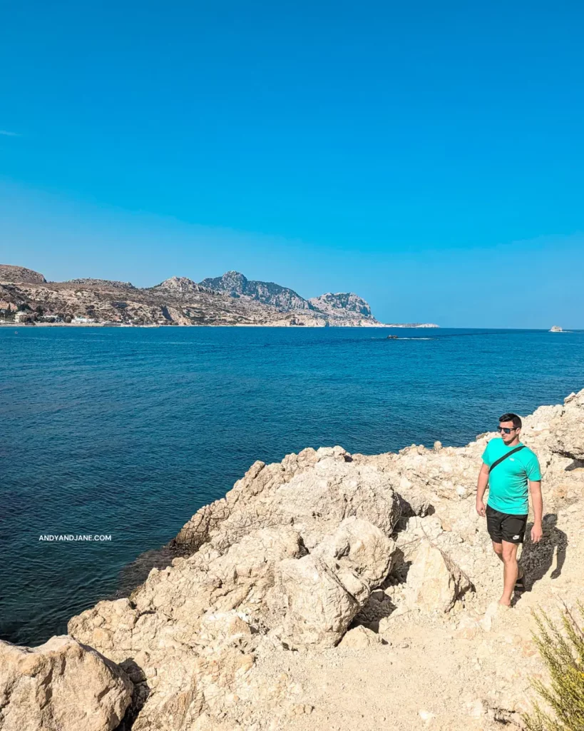 Andrew walking on a rocky path by the ocean in Stegna, enjoying the scenic view and the sound of crashing waves.