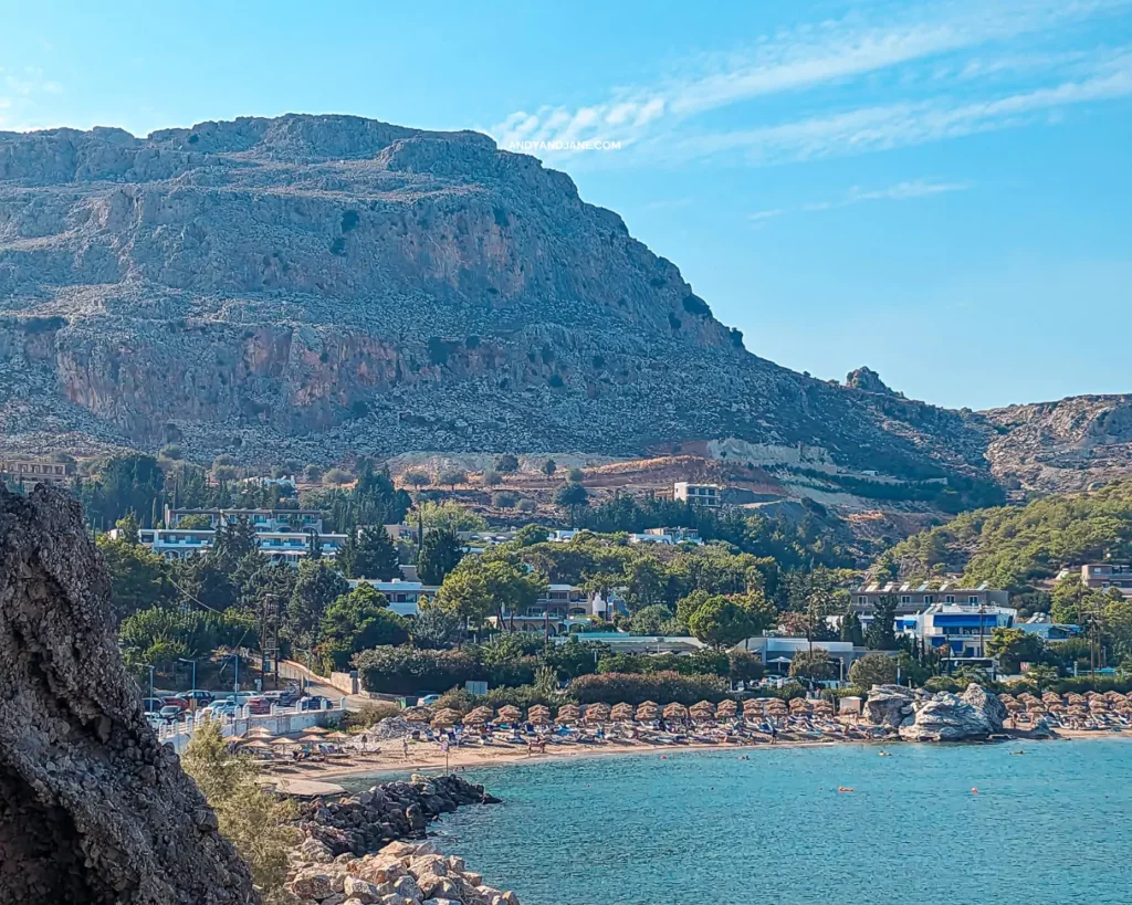 A scenic view of a majestic mountain overlooking the beautiful beach and charming town of Stegna in Rhodes.