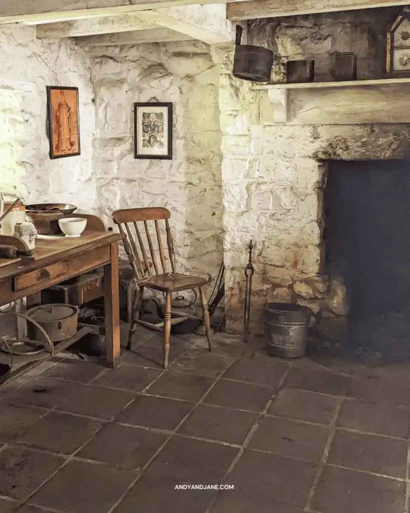 A cozy kitchen in a farmhouse with a wooden table, chairs, and a warm fireplace.