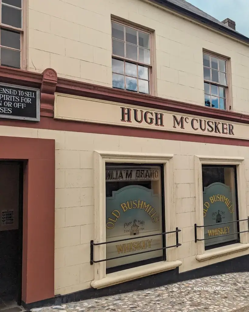 Hugh Mc Cusker's Pub with frosted windows saying 'Old Bushmill's Whiskey'. It's painted red & cream.