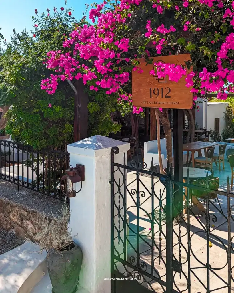 Gate to the 1912 Restaurant in Pefkos, with pink flowers surrounding the entrance.