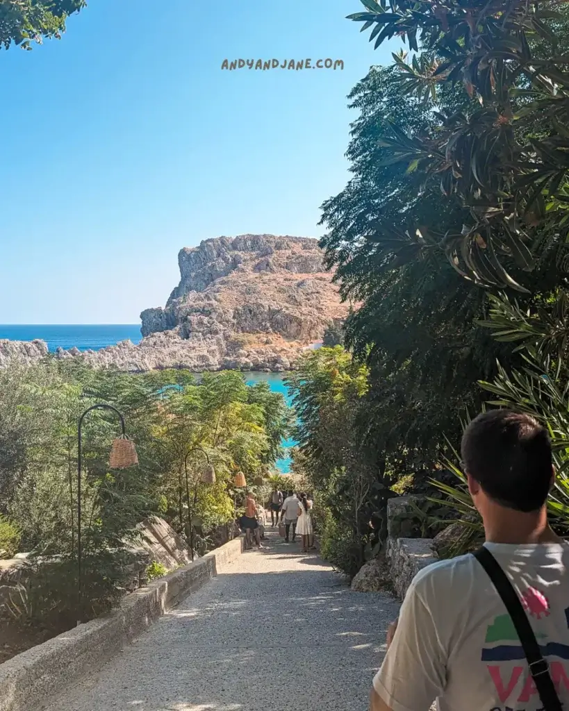 A tree lined footpath leading down to the blue water at St. Paul's Bay.