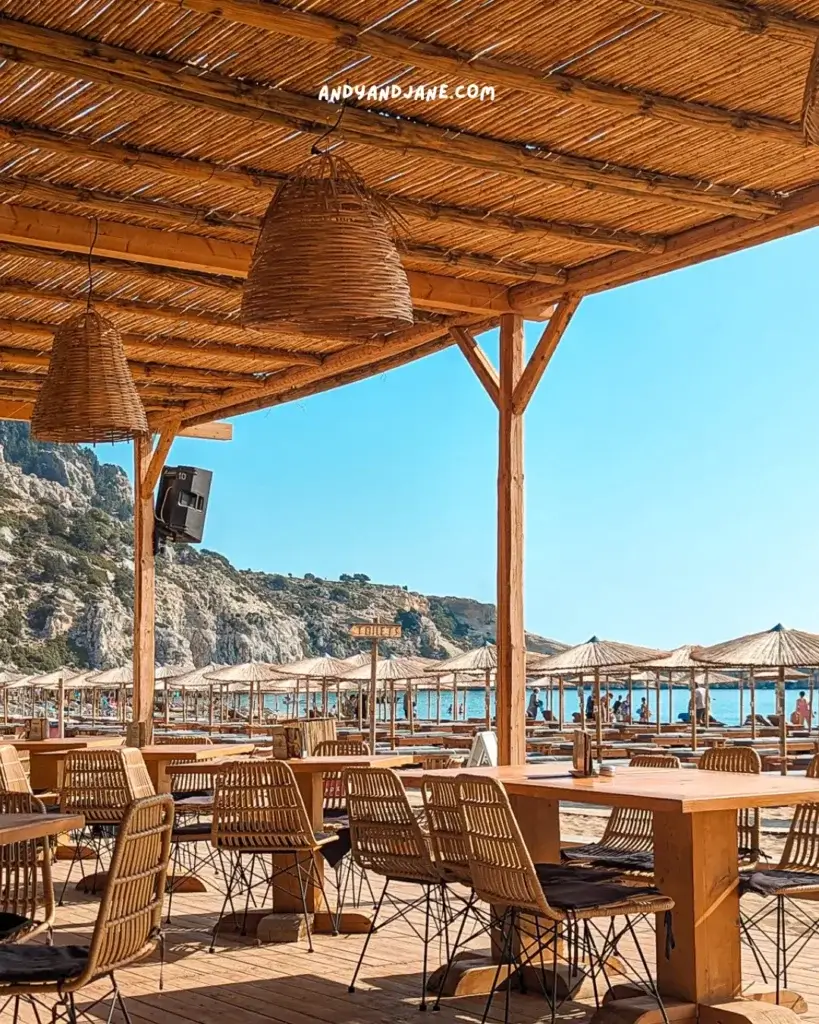 The tables & chairs at Ramal beach bar looking out to the sunbeds lining the beach & blue sky.