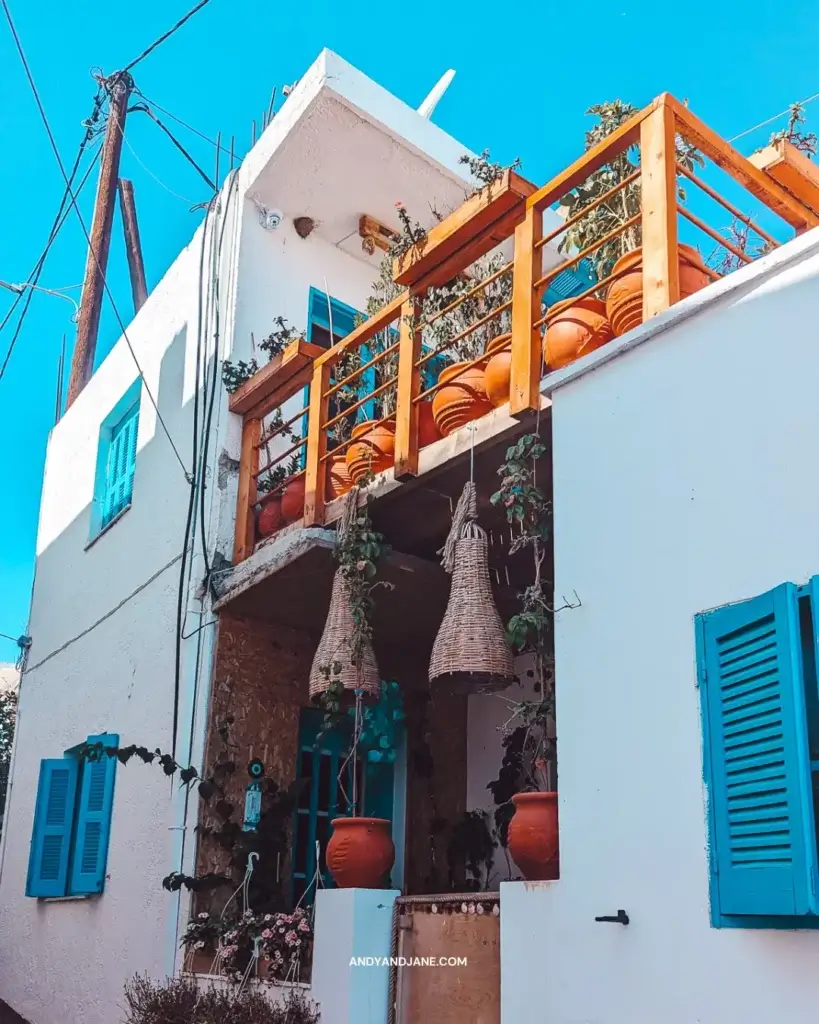 A house in Gennadi with blue shutters & a balcony full of terracotta plant pots.