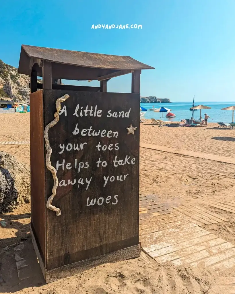 A beach hut at Tsambika Beach with the phrase 'A little sand between your toes helps to take away your woes' written on the side.