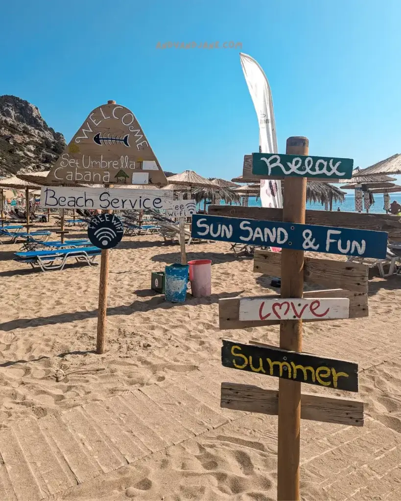 Wooden beach signs with the words 'relax', 'sun sand & fun', 'love' & 'summer' written on them.