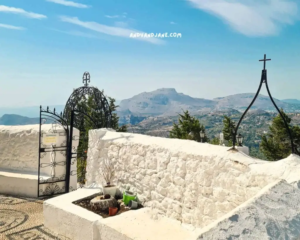 The white walls which enclose Tsambika Monastery overlooking a mountainous landscape in the distance.