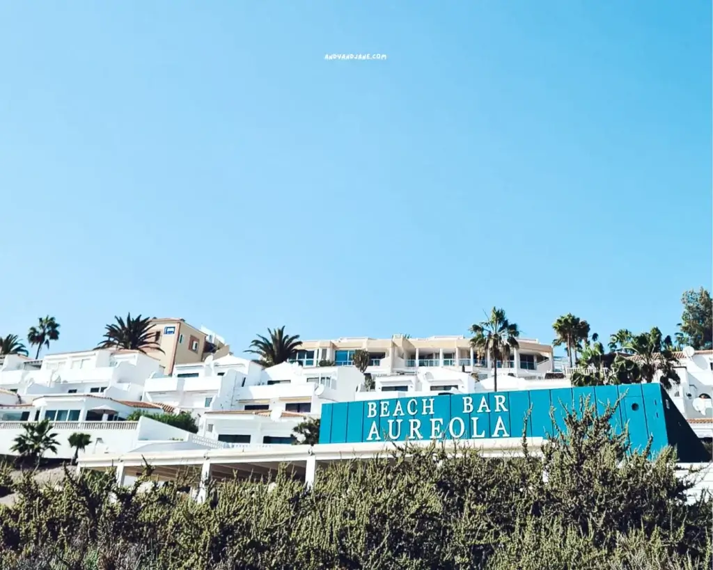 A blue building featuring a prominent sign that reads "Beach Bar Aureola," inviting visitors to enjoy refreshments by the beach.