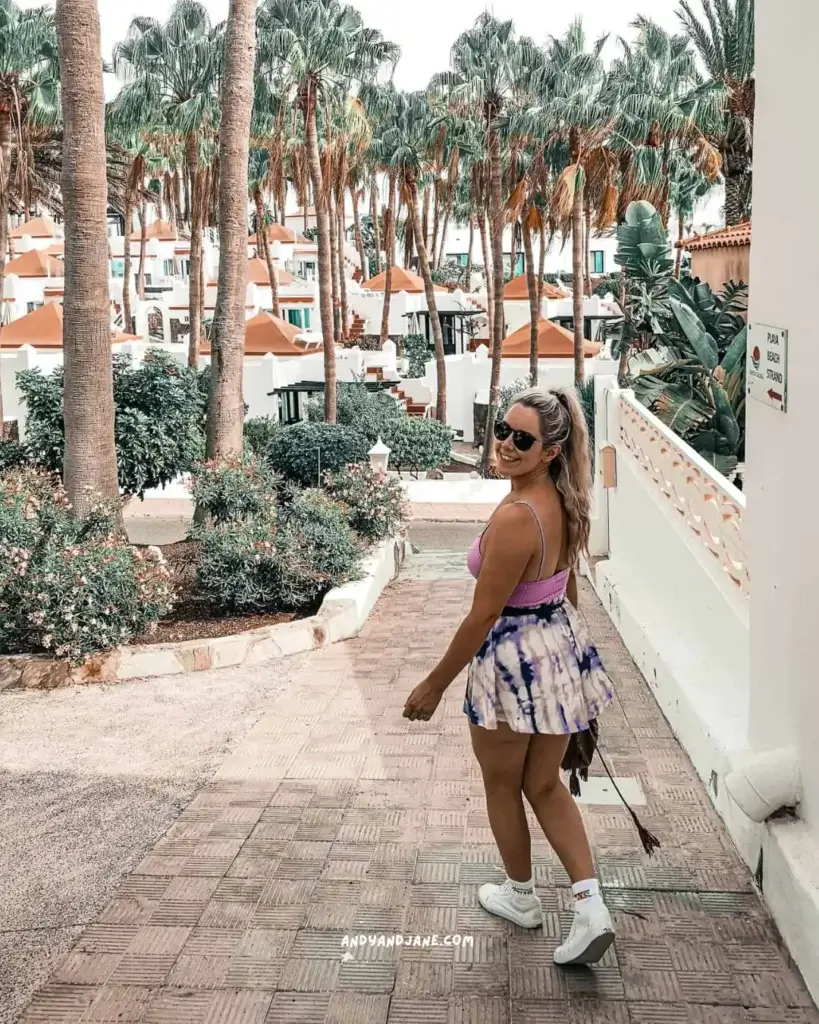 A woman walking down a palm tree lined alley in Costa Calma.