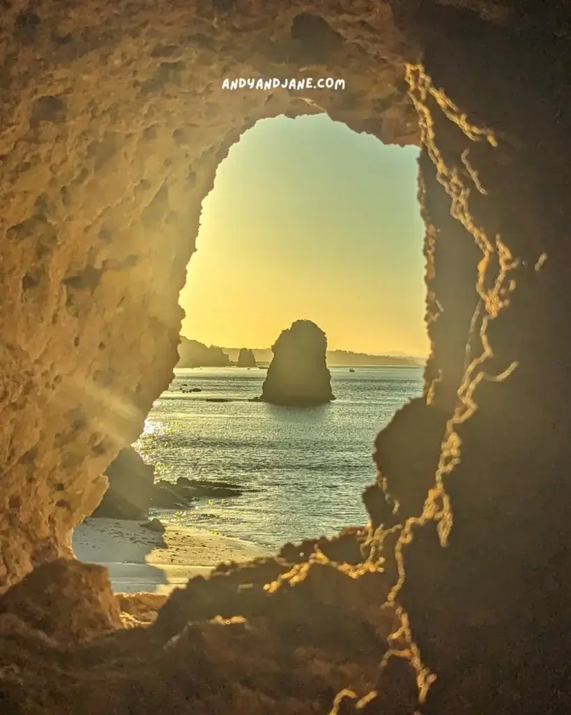 Looking out to the ocean and sunrise through a hole in the cliff at Praia Da Vigia.