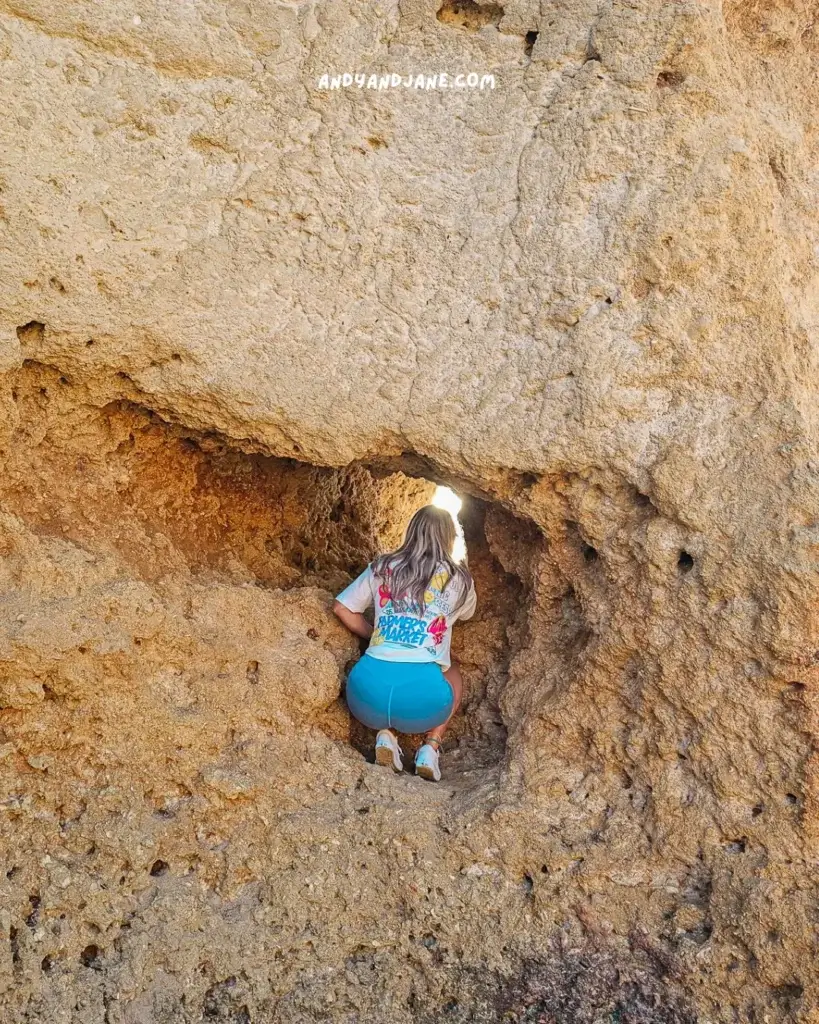 Jane climbing the rock to look through the gap towards the ocean.