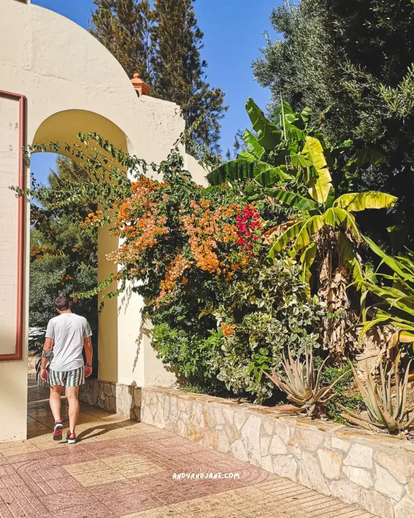 A man walking through an archway with colourful flowers surrounding it.