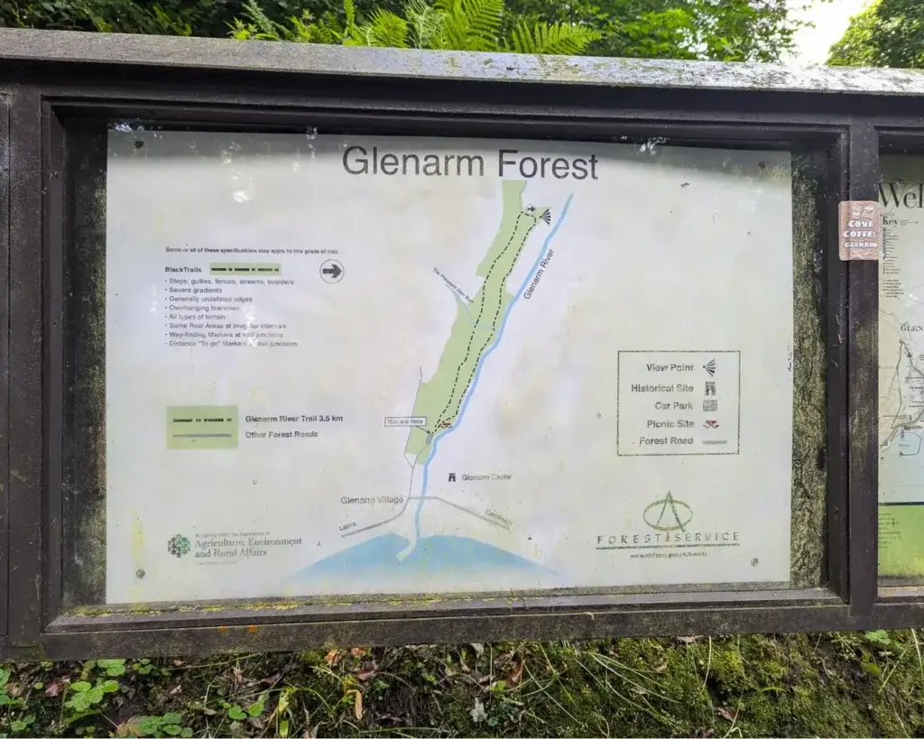 A weathered map display of Glenarm Forest with trails, signage icons, and foliage around.