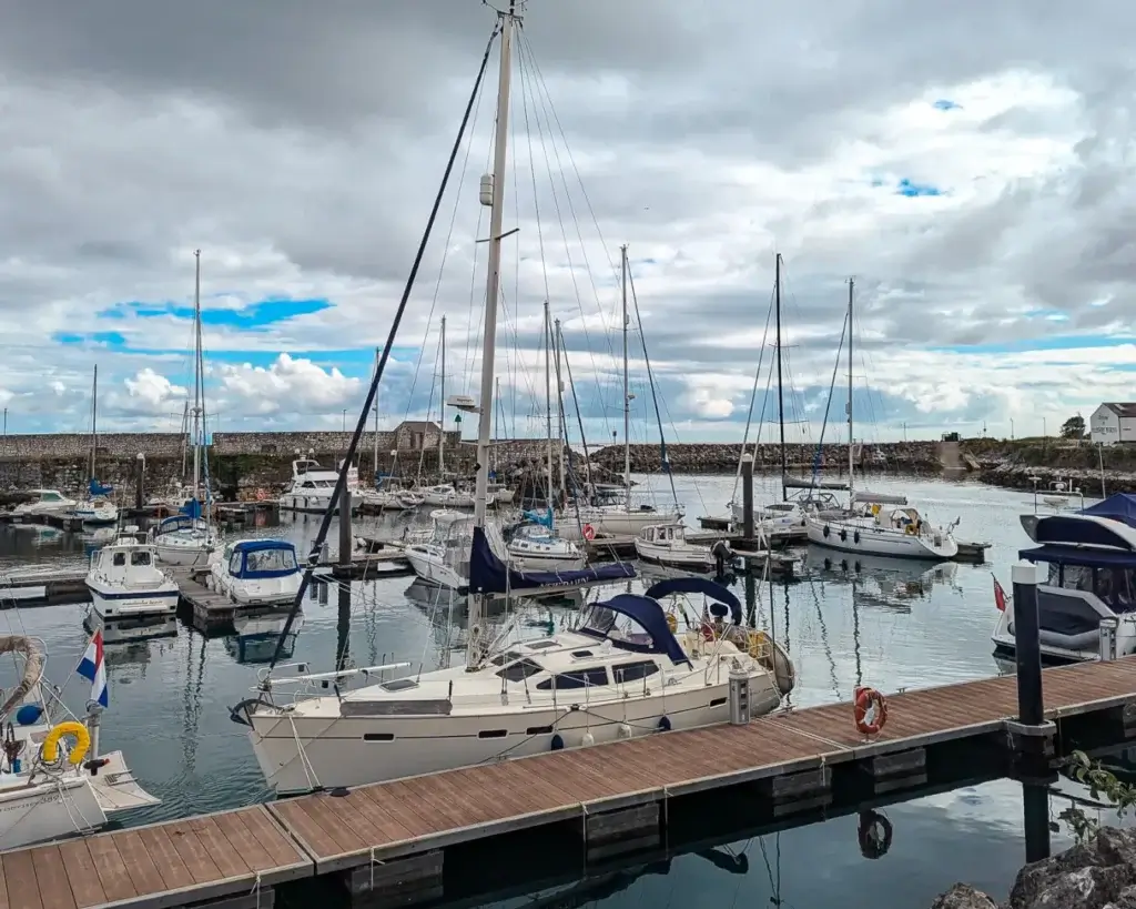 Glenarm Marina with various sailboats docked on a cloudy day.