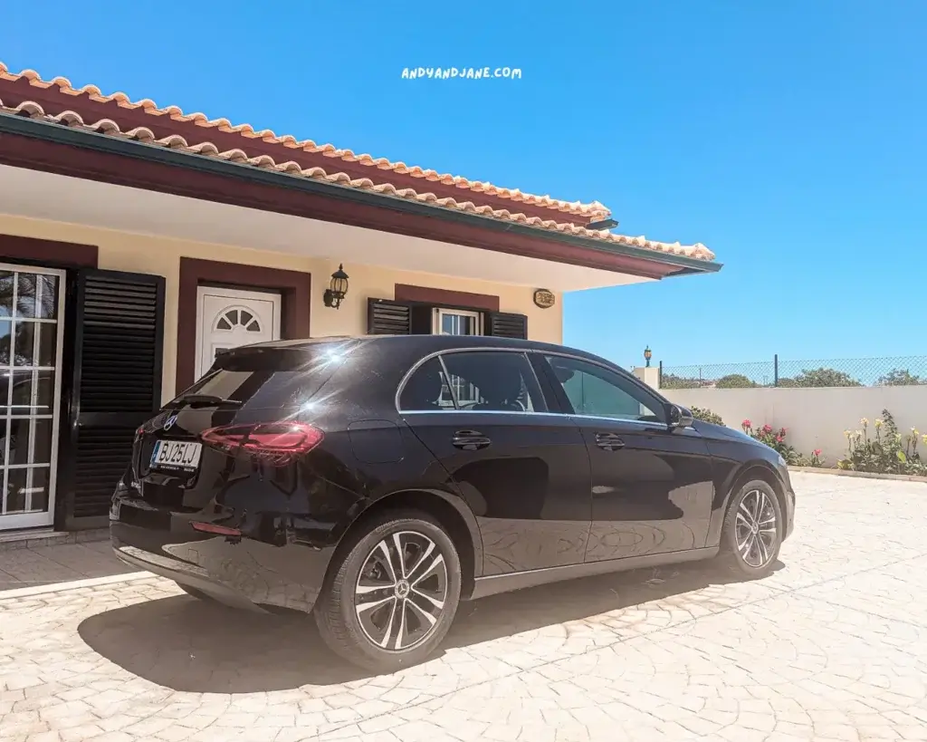 A black Mercedes car sitting outside a villa in Portugal with an orange roof.