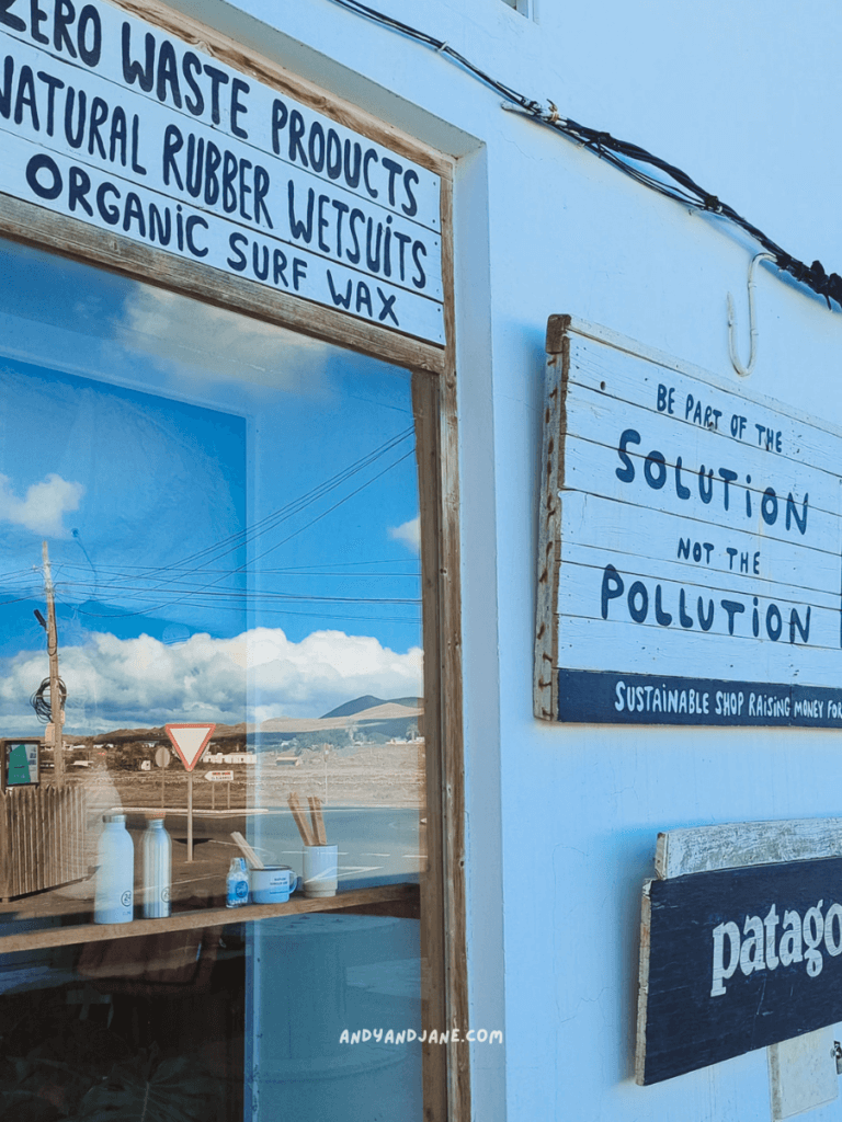 A sustainable shop exterior featuring signs for eco-friendly products and a message promoting pollution solutions near a scenic landscape.