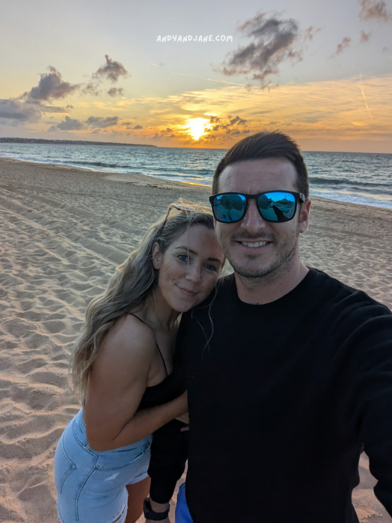 A couple enjoys a sunset on Praia Dos Salgados, with golden sand and gentle waves in the background, capturing a moment of intimacy and warmth.